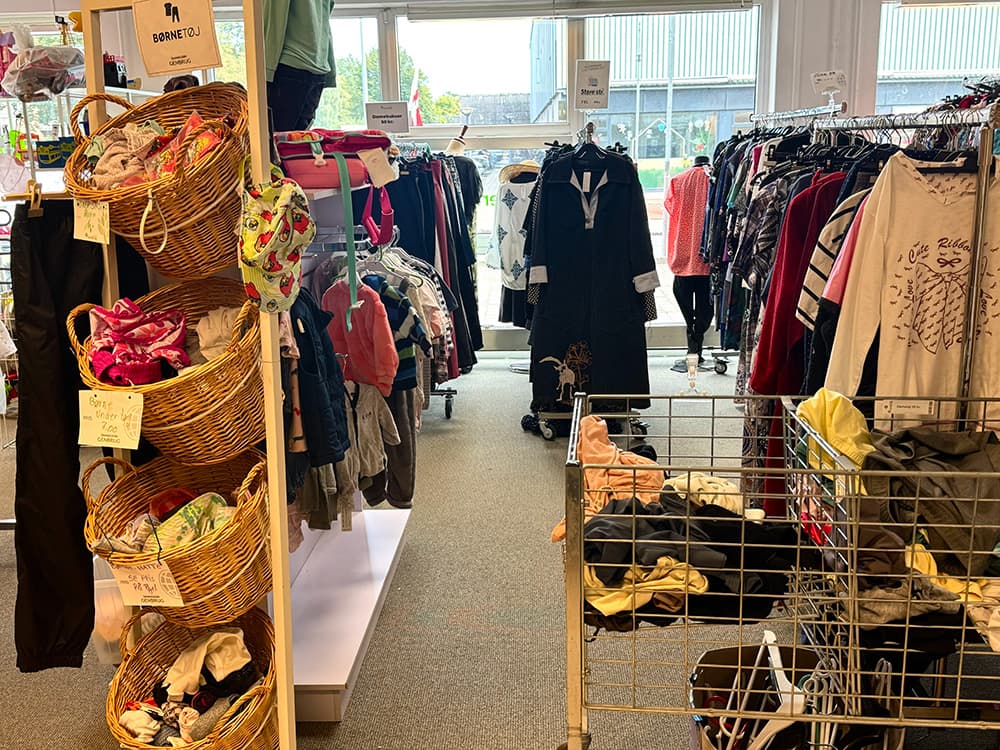 Genbrugsbutik med stativer med tøj og kurve med børnetøj